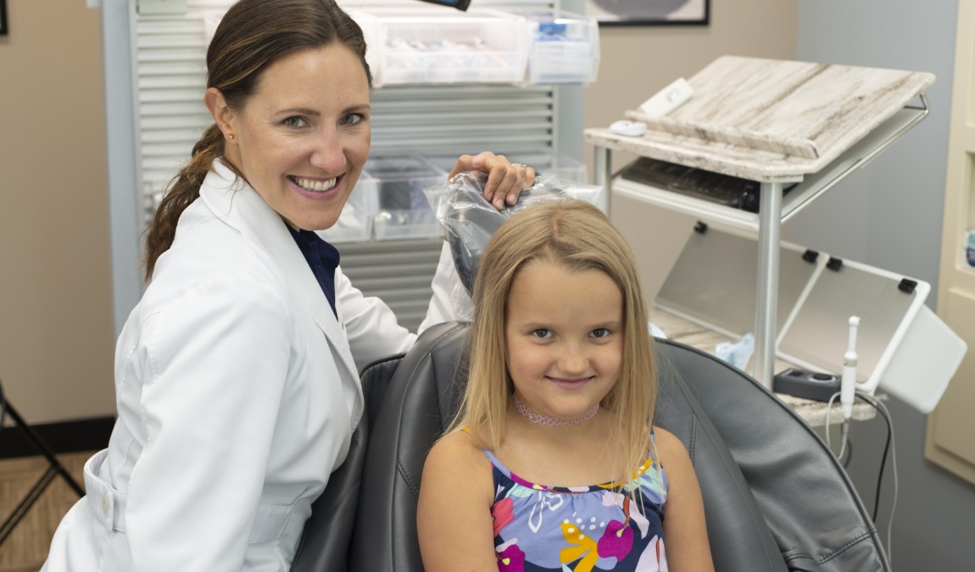 Young girl smiling with her dentist before getting athletic mouthguard in Arlington Heights
