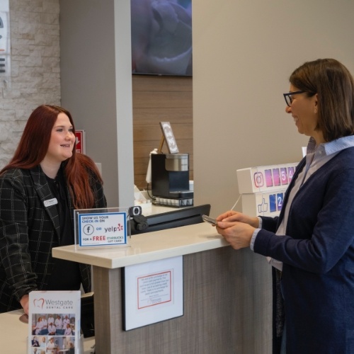 Woman talking to dental team member at front desk