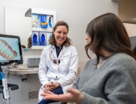 Woman in gray sweater talking to her cosmetic dentist