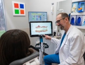 Dentist pointing to models of teeth on screen