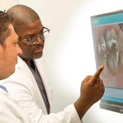 Dentist pointing to image of decayed tooth needing tooth extraction