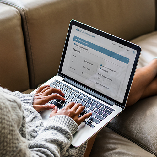 Woman sitting on couch typing on laptop