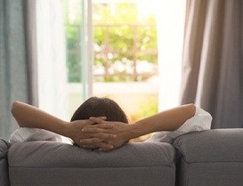 Person relaxing on couch with their hands behind their head