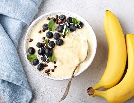 Two bananas next to bowl of yogurt