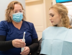 Dental team member showing an electric toothbrush to a patient