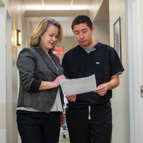 Dentist and patient looking at a paper in hallway