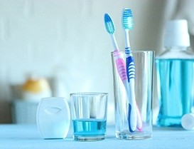 Two toothbrushes in glass next to mouthwash