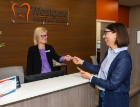 Woman handing a card to dental office receptionist