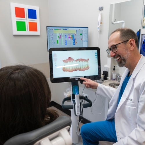 Smiling dentist showing digital scans of teeth to a patient