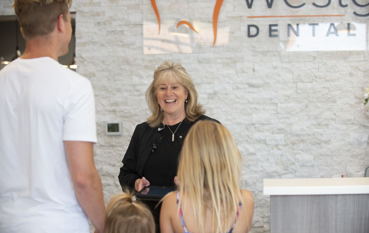 Dental team member greeting a family of three in reception area