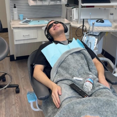 Man relaxing in dental chair with blanket and sunglasses