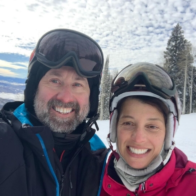 Smiling man and woman in ski gear on snowy mountain