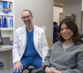 Woman in gray sweater smiling next to her dentist