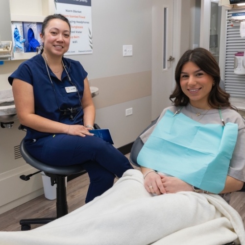 Dental team member smiling next to patient in treatment chair