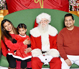 Doctor Dev and her husband and child visiting Santa Claus