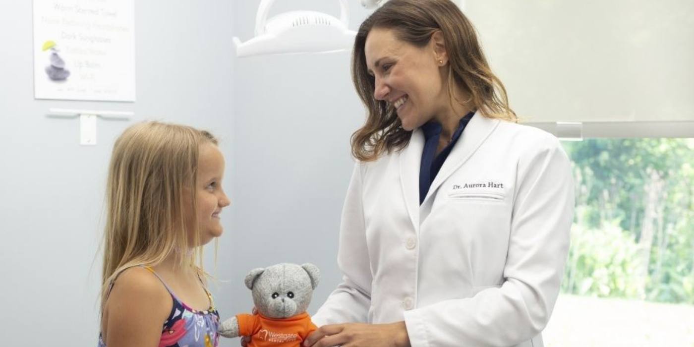 Doctor Hart giving a teddy bear to a young girl