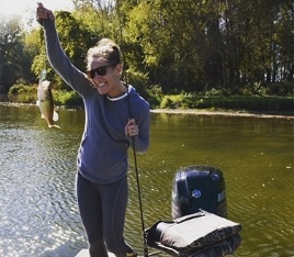 Doctor Hart on a boat holding up a fish she just caught