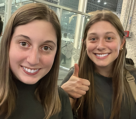 Two smiling young women giving thumbs up