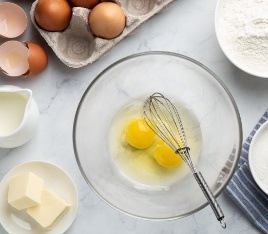 Mixing bowl with eggs and a whisk