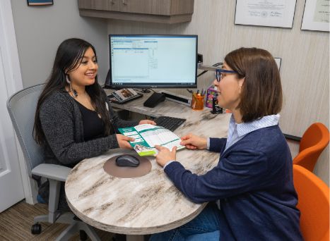 Dental team member showing a pamphlet to a patient across desk