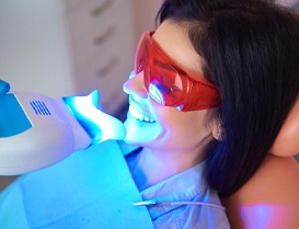 Woman getting her teeth professionally whitened in dental chair