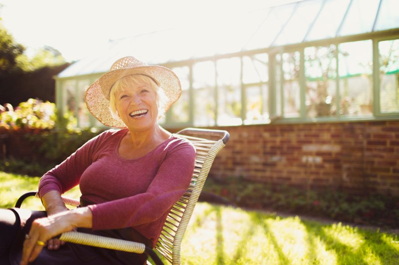 an older woman sitting outside smiling with dental implants